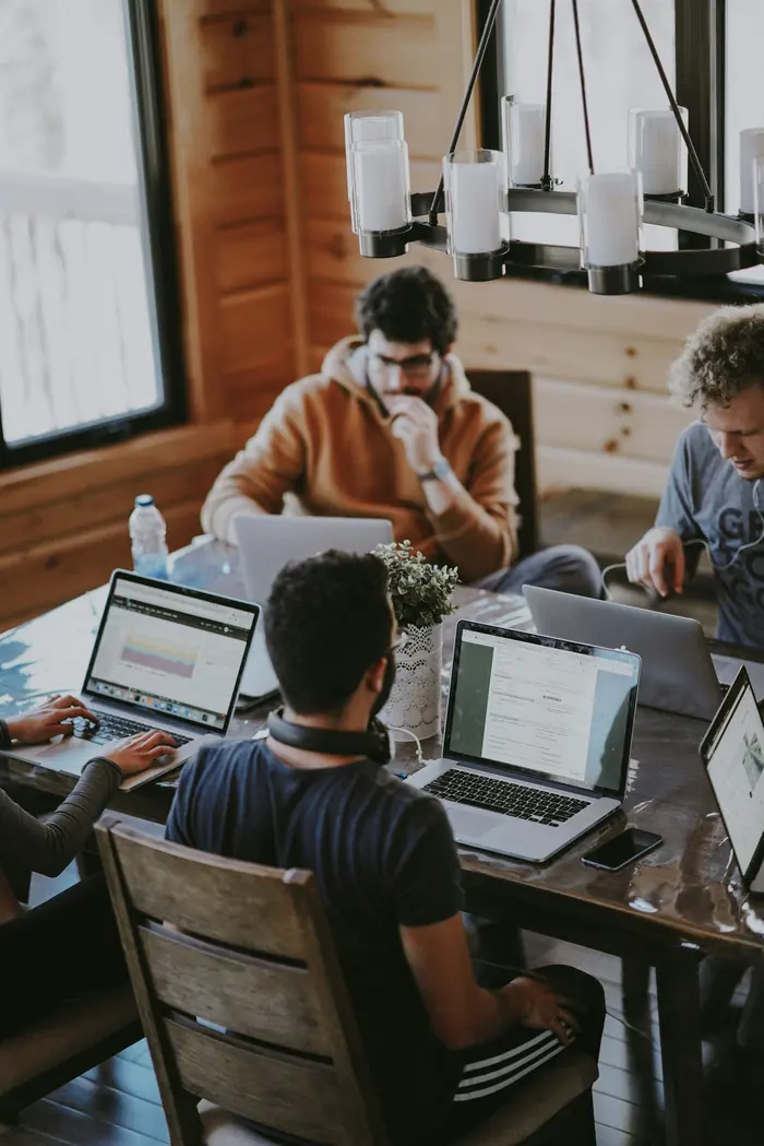 Une équipe qui travaille ensemble sur ordinateurs portables autour d'une table, dans une ambiance chaleureuse et collaborative